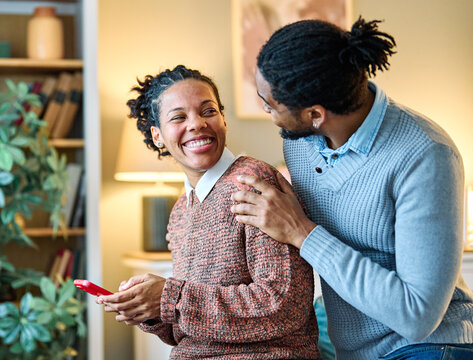 Happy young couple having fun using smartphone  during oline video call conversation or shopping or using an app at home