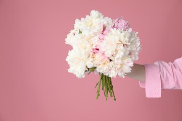 Woman with bouquet of beautiful peonies on pink background, closeup. Space for text