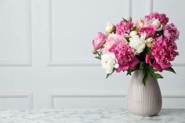 Bouquet of beautiful peonies in vase on white marble table indoors, space for text
