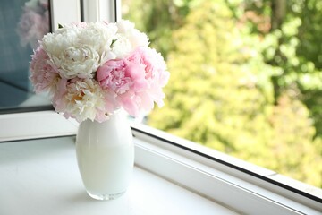 Beautiful peonies in vase on windowsill indoors. Space for text