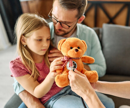 Young father with little daughter child do checkup examination at pediatrician in clinic. Healthcare concept. Woman doctor hold stethoscope listen to girl patient heart chest in hospital. - Powered by Adobe