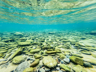Underwater view on the beach in Ios island, Greece. White fish swim on the rocky bottom of the sea.