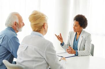 Fototapeta premium Senior couple having a meeting with an agent, businesswoman, salesperson or doctor in his office