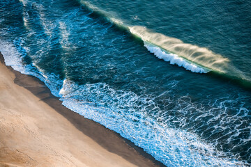 Atlantic ocean coast in Nazare, Portugal. Waves on the beach at sunset.