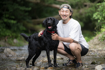 Large dog and owner playing in the river Hot dog looking at the camera playing in the river in summer
