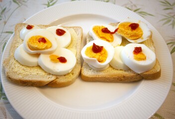 Bread and margarine with sliced egg and red gold sauce on plate.