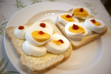 Bread and margarine with sliced egg and red gold sauce on plate.