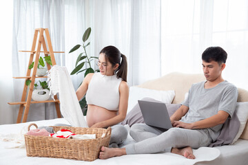 Asian pregnant beautiful mother sitting folding and prepare daughter's clothes while father is...