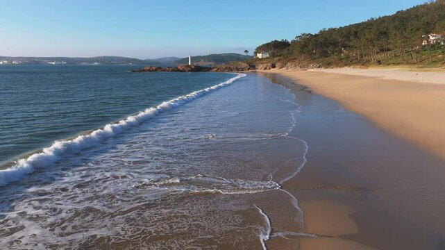 Flying Over The Waves At Praia do Lago With Fazo baliza do Lago In The Background In Muxia, A Coru&ntilde;a, Spain. - aerial shot