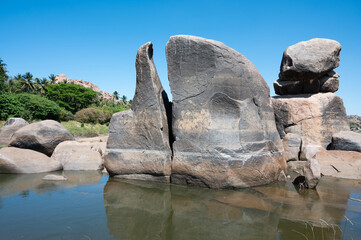 Cyclopean granite boulder in Tungabhadra river, water reflection, rocky terrain landscape, Hampi,...