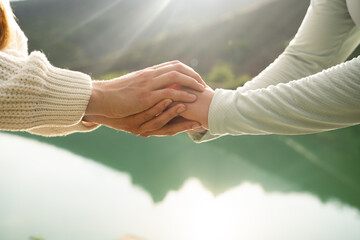 Close-up of two women holding hands in nature, symbol of female friendship, trust, empathy and...