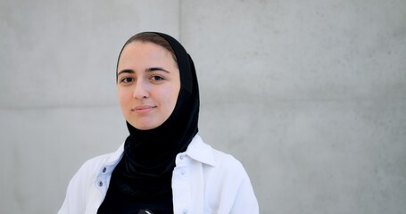 Muslim woman in hijab displaying varied facial expressions from contemplative to intense, standing against minimalist concrete wall backdrop
