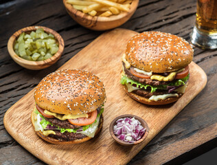 Hamburgers and French fries on the wooden tray.