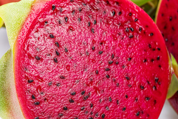 Dragon fruit cut in half with red pulp and black seeds black seeds close up.