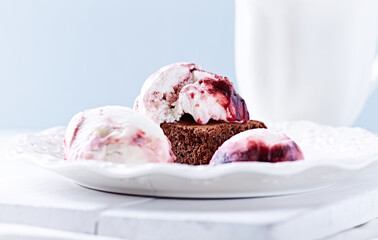 Strawberry ice cream with chocolate and cherry syrup on chocolate brownie. Selective focus.