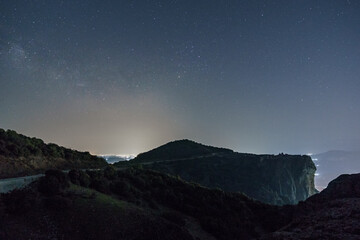 Stars and Milkyway over rock formations of Meteora with Monastery of the Holy Trinity on top of rocks during night time, Kalambaka, Thessaly, Greece