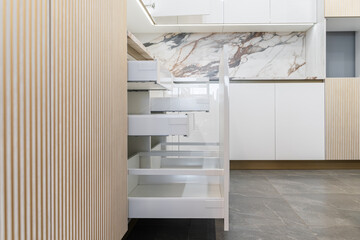 large corner built-in kitchen in white and beige shades. Modern kitchen with upper and lower...