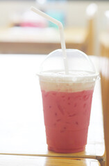 Pink iced milk on a wooden table at cafe