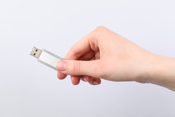 Man with modern flash drive on light grey background, closeup