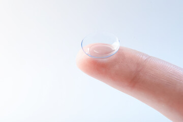 Woman with contact lens on light background, closeup. Space for text