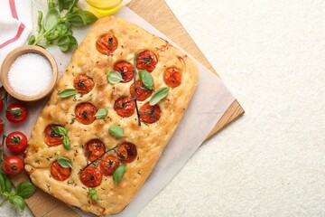 Delicious focaccia with tomatoes and spices on beige textured table, flat lay. Space for text