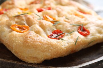 Delicious focaccia with tomatoes and rosemary on table, closeup
