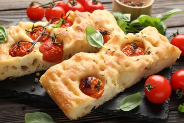 Pieces of delicious focaccia with tomatoes and spices on table, closeup