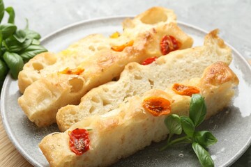 Pieces of delicious focaccia with tomatoes and basil on gray table, closeup