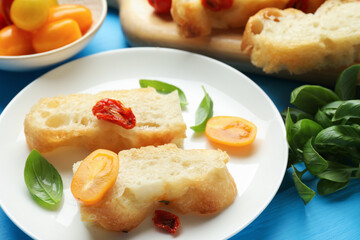 Pieces of delicious focaccia with tomatoes and basil on light blue wooden table, closeup