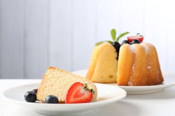 Tasty bundt cake with powdered sugar, berries and mint on white table, closeup