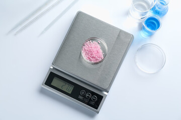 Scale with Petri dish of sample and other laboratory equipment on white background, flat lay