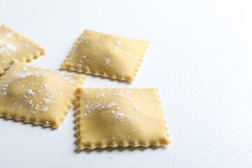 Uncooked ravioli on white table, closeup view. Space for text