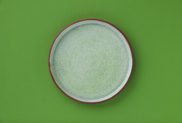 One empty plate on green background, top view