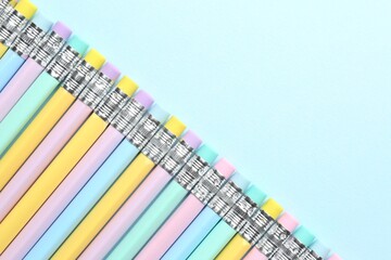 Graphite pencils with erasers on light blue background, flat lay. Space for text