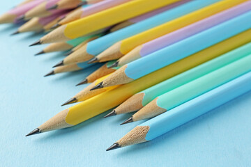 Many graphite pencils on light blue background, closeup