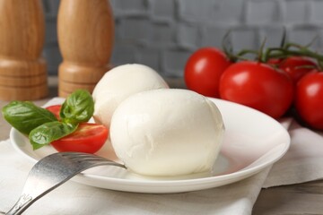 Tasty mozzarella cheese balls, tomatoes and basil on table, closeup