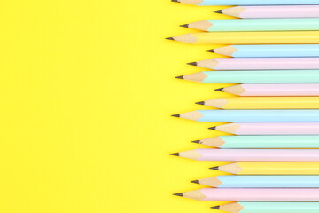Many graphite pencils on yellow background, flat lay. Space for text