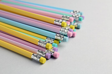 Many graphite pencils with erasers on light grey background, closeup. Space for text