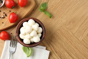 Tasty mozzarella balls, tomatoes, peppercorns and basil on wooden table, flat lay. Space for text