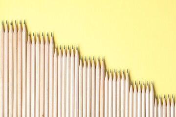 Many graphite pencils on yellow background, flat lay. Space for text