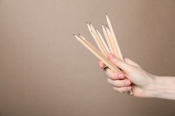 Woman with graphite pencils on beige background, closeup. Space for text