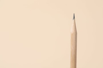 One graphite pencil on beige background, closeup. Space for text