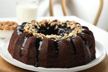 Delicious chocolate bundt cake with nuts on table indoors, closeup