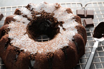 Tasty bundt cake with glaze and chocolate pieces on grey table, closeup