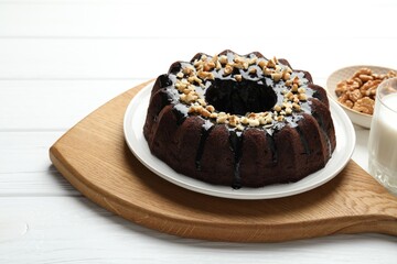 Delicious chocolate bundt cake with nuts on white wooden table, closeup