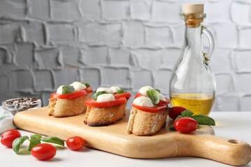 Tasty sandwiches with mozzarella cheese, tomatoes and basil on white table, closeup