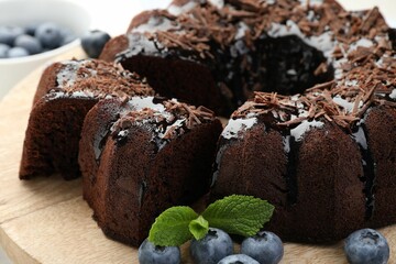 Delicious bundt cake with blueberries, mint and chocolate shavings on table, closeup