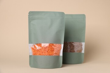 Zipper stand-up pouches with lentils and seeds on beige background. Mockup for design