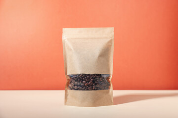 One zipper stand-up pouch with coffee beans on white table against red background. Mockup for design