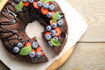Delicious chocolate bundt cake with strawberries, mint and blueberries on wooden table, top view